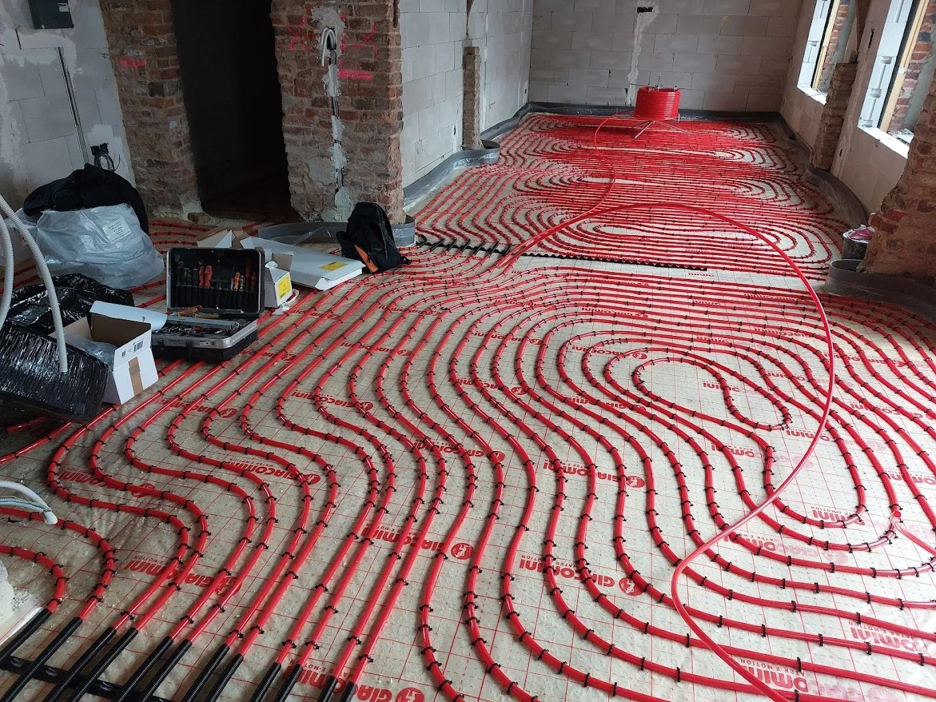 Boucles rouges de plancher chauffant posées sur isolant avant la chape, chantier IDEP à Tournai